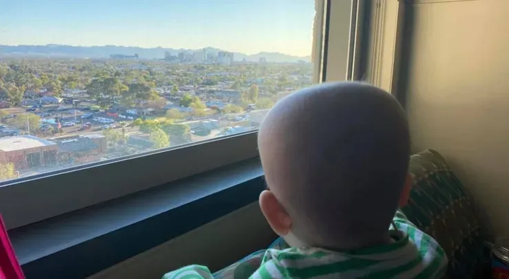 Jazmine gazing out a high hospital window at the Phoenix skyline and mountains beyond.