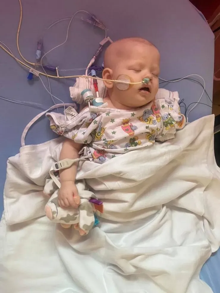 Jazmine asleep in her hospital bed, holding a soft plush toy close.