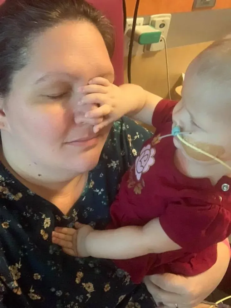 Jazmine reaching up to touch her mom's face as her mom holds her close.