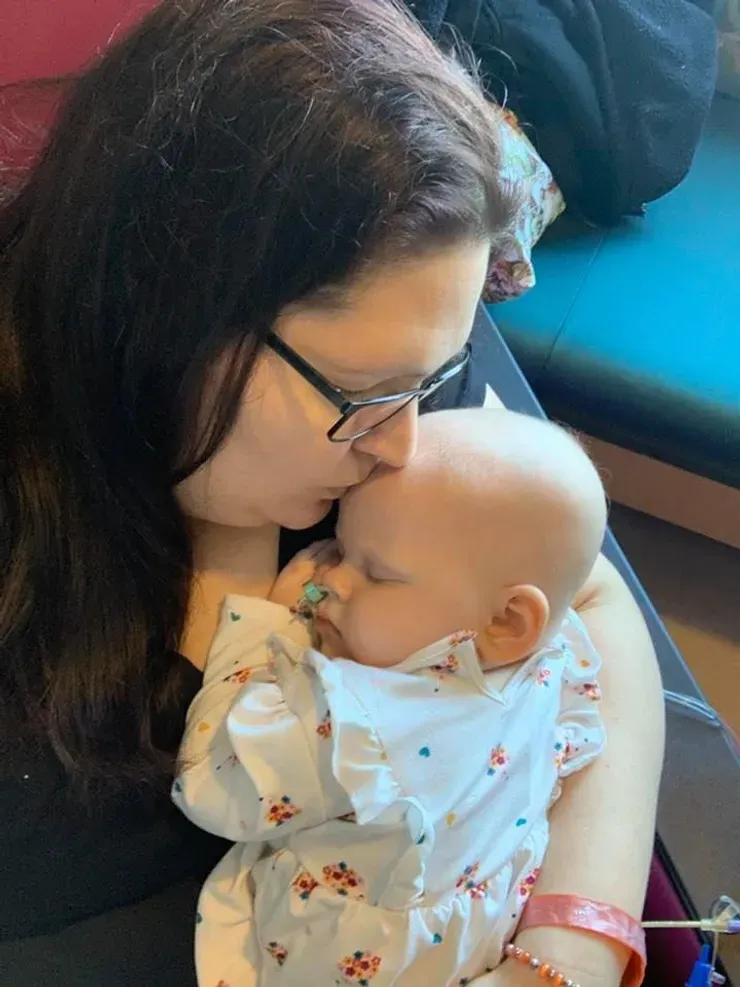 Jazmine's mom kissing her forehead as she sleeps peacefully in her arms.